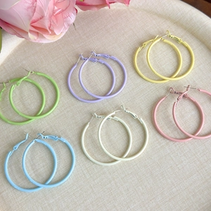 Detailed close-up of six pairs of macaron-colored matte hoop earrings in a display tray