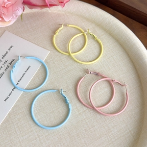 Close-up of pastel macaron-colored hoop earrings set on a textured beige display tray