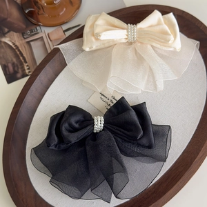 Detailed macro view of satin and organza bow hair clip with triple-row pearl beads