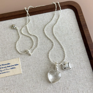 Close-up of beaded silver necklace and bracelet set with transparent heart pendants