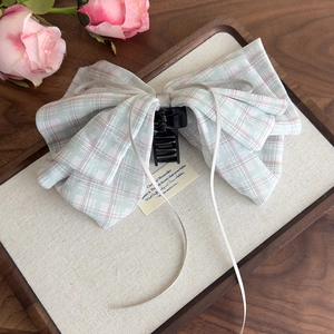 Detailed view of sweet plaid bow hair claw clip with ribbons on a rustic wooden tray