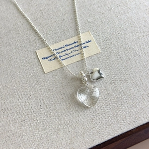 Close-up of double heart pendant necklace with transparent and silver finish on bead chain