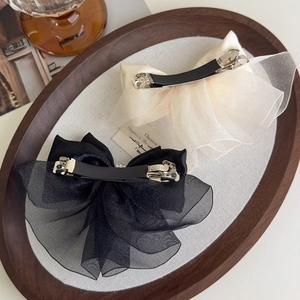 Detailed macro view of satin organza bow hair clips in black and beige with spring clips
