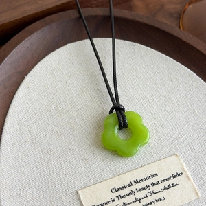 Détail d'un pendentif fleur en acrylique vert vif sur un collier en cordon noir