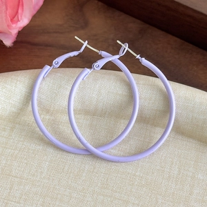 Detailed macro view of lavender purple matte hoop earrings on textured background
