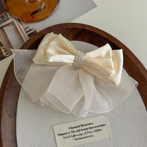 Detailed close-up of ivory satin and organza bow hair clip with luxury pearl beads