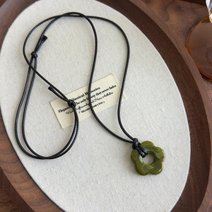 Gros plan détaillé du pendentif fleur en résine vert foncé avec texture marbrée