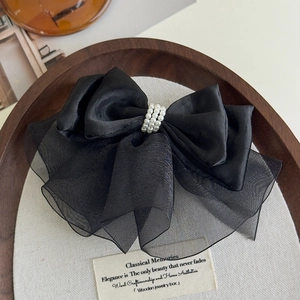 Close-up of black satin and organza bow hair clip with white faux pearl details