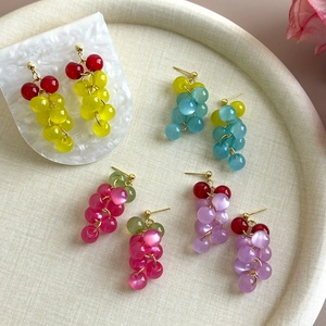 Close-up of colorful cat-eye grape cluster earrings in yellow blue pink and purple on tray