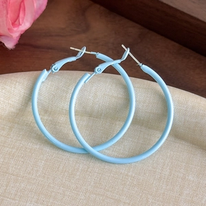 Macro shot of macaron blue matte large hoop earrings on a textured jewelry tray