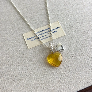 Close-up of a double heart pendant with yellow resin and silver metal on a bead chain
