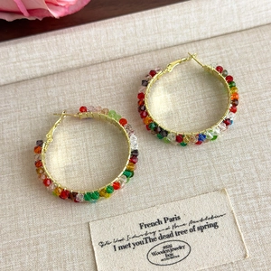 Détail des boucles d'oreilles créoles avec perles de cristal colorées style bohème