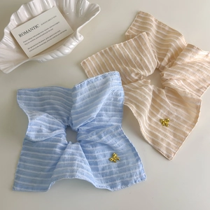 Détail de chouchous rayés bleu et beige avec d'élégants nœuds en métal doré raffinés