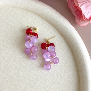 Detail of handmade grape earrings with red and purple beads and gold-tone studs