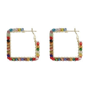 Détail de boucles d'oreilles carrées en fil doré avec des perles de cristal colorées