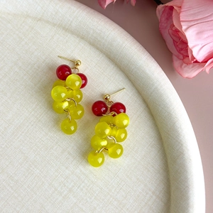 Close-up of sweet grape style beaded earrings with red and yellow cat eye stones