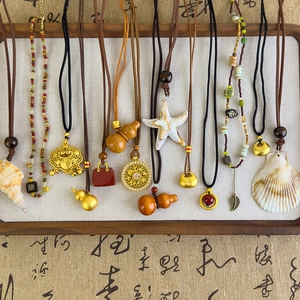 Détail de pendentifs ethniques avec coquillages, courges en bois et agate rouge sur cordons