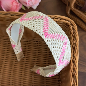Detail of bohemian raffia headband with pink geometric pattern in a rustic basket