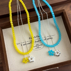 Gros plan d'un collier double épaisseur perlé avec pendentifs fleurs colorées en boîte