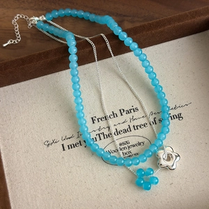 Détail du collier double rang avec perles en verre bleu et pendentif fleur argent