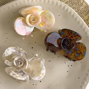 Three elegant acetate rose hair claws in pink, tortoiseshell, and white marble textures