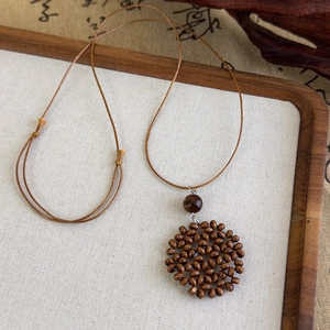 Gros plan d'un pendentif disque perlé marron sur cordon ajustable au style ethnique rétro