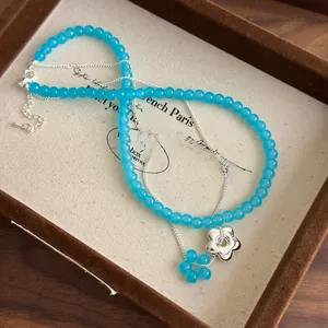 Détail d'un collier double rang avec perles bleues et pendentif fleur en argent sur plateau