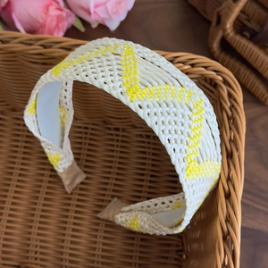Detail of bohemian cream and yellow woven headband on rustic brown rattan background