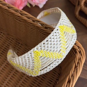 Detail of bohemian woven headband featuring yellow and beige geometric straw pattern