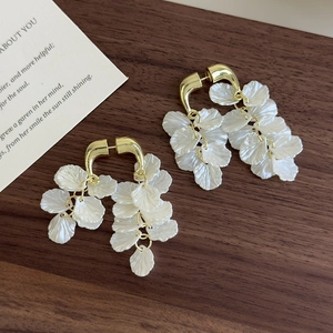Detailansicht von champagnergoldenen Muschelblüten-Ohrringen mit eleganten Fransen