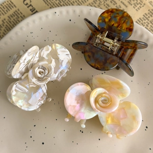 Detailed view of camellia hair claws in acetate marble finish and tortoiseshell patterns