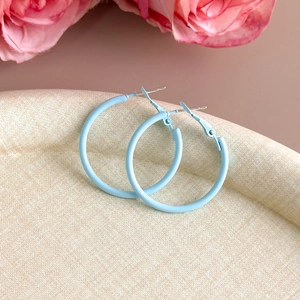 Macro detail of light blue matte hoop earrings on beige textured display tray