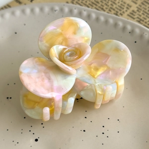 Macro view of French vintage camellia hair claw with marble texture on ceramic plate