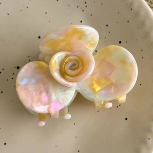 Detailed view of an elegant acetate camellia hair claw clip with a pearlescent marble finish