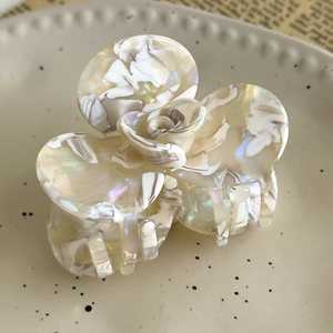 Macro detail of camellia hair claw clip with cream marble texture and pearl luster