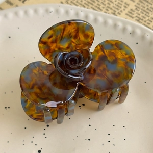 Close-up of tortoise shell flower hair claw clip with rose detail on a ceramic plate