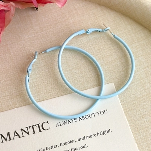 Detail view of light blue metal hoop earrings with minimalist circular design and smooth finish