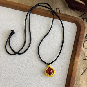 Détail macro d'un collier rétro chinois avec anneau doré et perle de cornaline rouge
