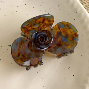 Detailed top view of a French camellia hair claw with vintage amber acetate texture