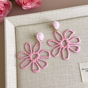 Detail of pink hand-woven raffia flower earrings for summer beach vacations