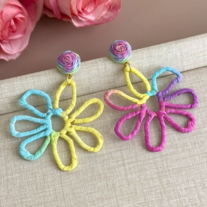 Detail shot of multi-color raffia woven flower earrings with handmade texture and vibrant colors