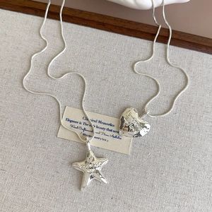 Detail of silver snake chain necklaces with textured heart and star promise charms