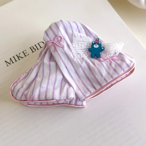 Détail de moufles bébé rayées roses avec bords en dentelle, nœud et décoration d'ours