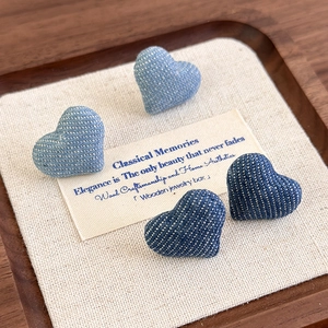 Retro denim fabric heart stud earrings in light and dark blue shades on a wooden tray