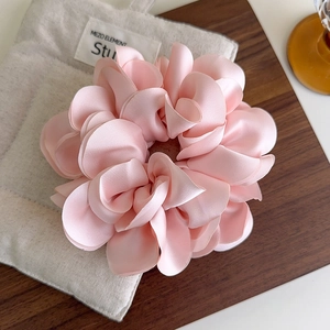 Détail d'un chouchou en satin rose avec volants superposés sur un plateau en bois