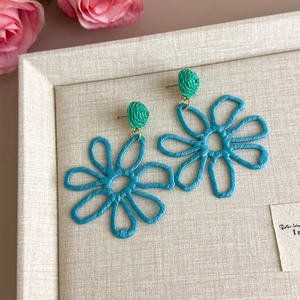 Detailed macro view of handmade turquoise raffia flower earrings for summer beach vacations