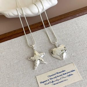 Detail of silver snake chain necklace with hammered star and heart engraved pendants