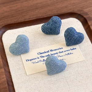 Denim heart earrings with white polka dots in dark and light blue displayed on wood
