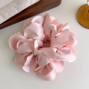 Détail d'un chouchou fleur en satin rose multicouche sur un plateau élégant