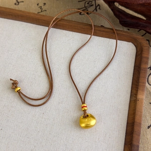 Détail du pendentif serrure en or mat avec caractère Fu sur cordon tressé